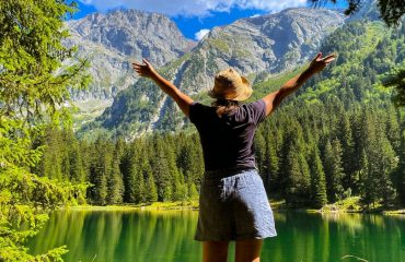 a woman standing in front of a mountain lake
